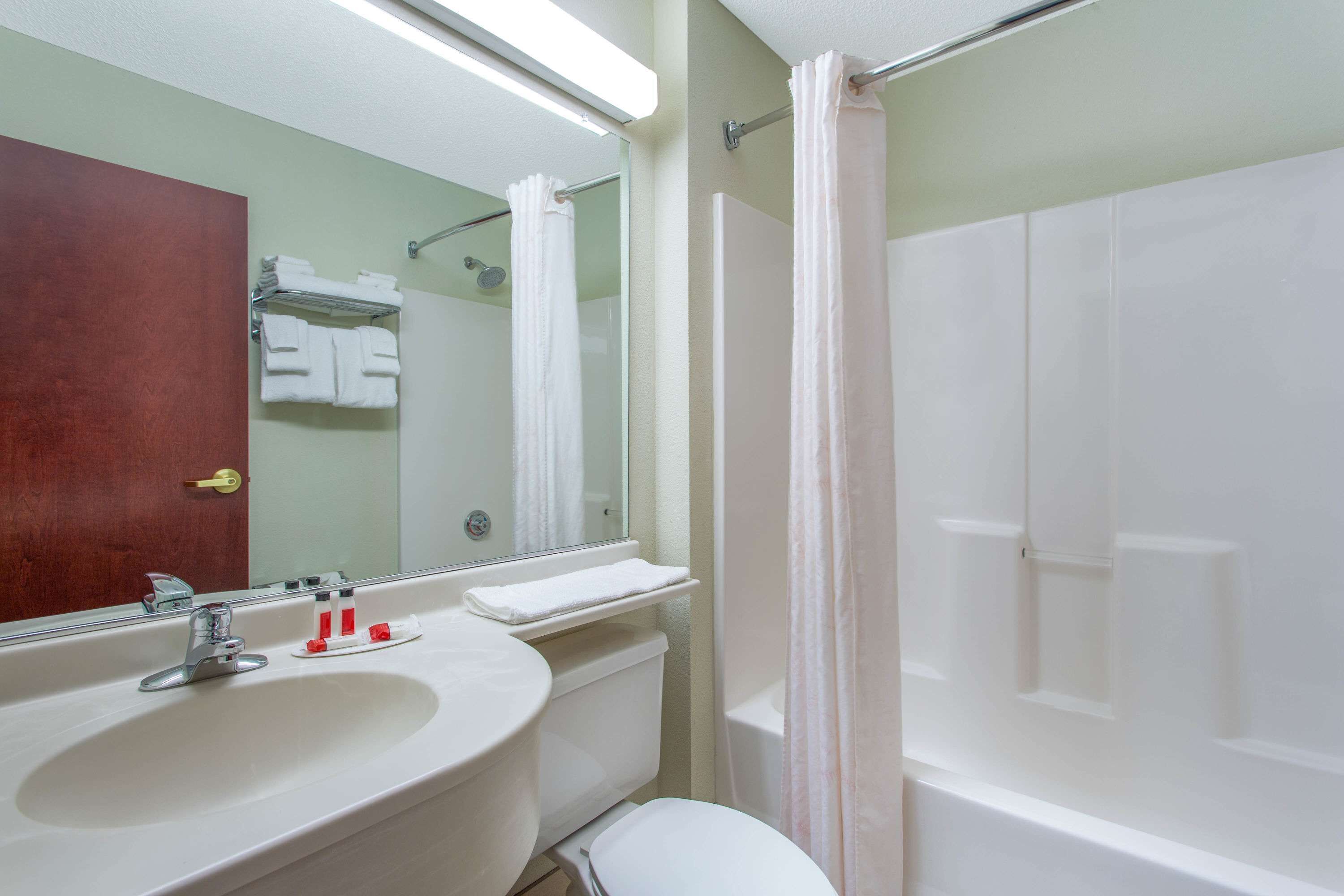 Een badkamer met een wastafel, spiegel, toilet en douche.