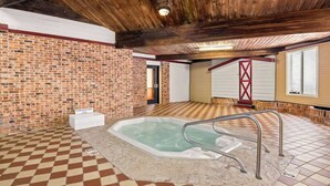 Un espace spa doté d’un jacuzzi, de poutres en bois au plafond et d’un sol à carreaux.