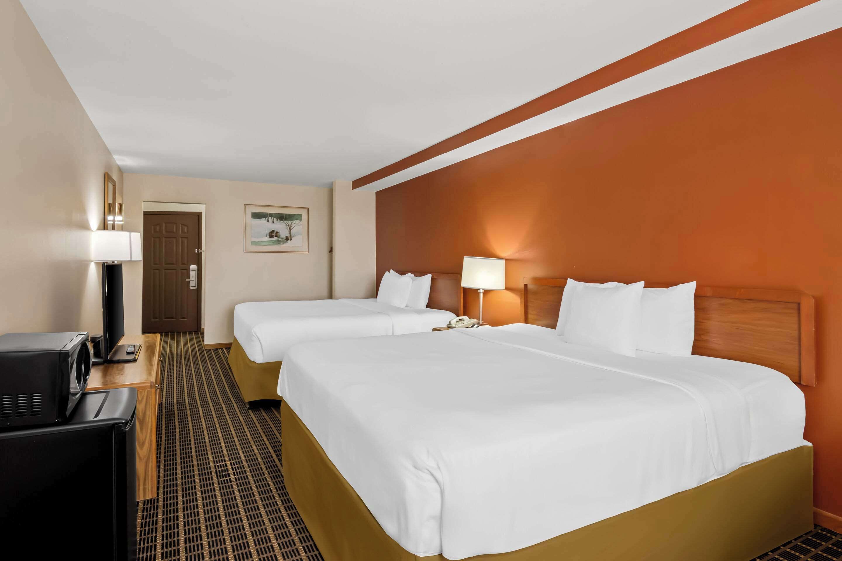 Habitación de hotel con dos camas, televisión, escritorio y lámpara.