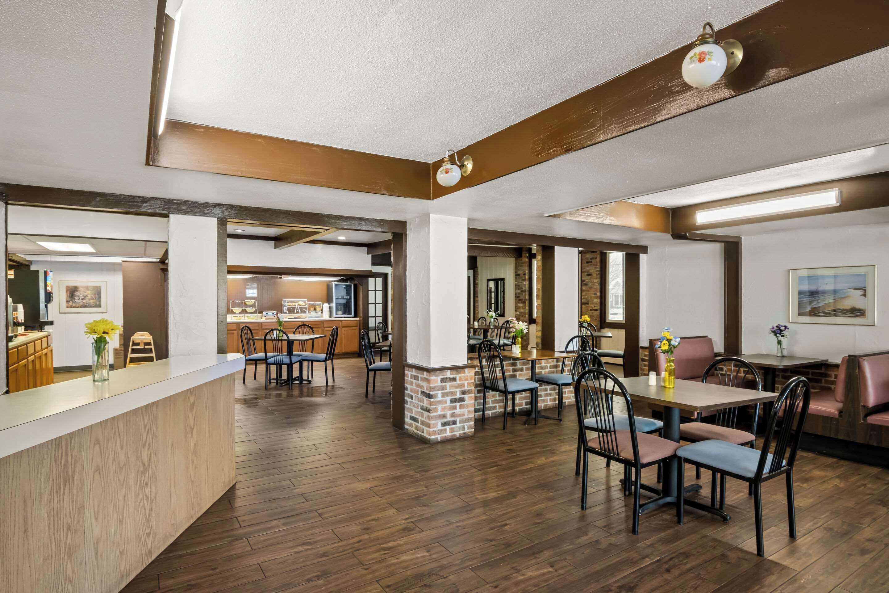 Un'ampia sala da ristorante con pavimento in legno, un bancone centrale e diverse aree di seduta, tra cui cabine e tavoli.