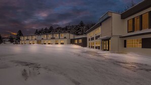 Un bâtiment moderne doté de nombreuses fenêtres et d’un toit plat, entouré d’un paysage enneigé.