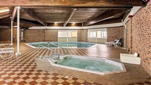 Un espace piscine comprenant deux bains à remous, des carreaux de sol à motifs et un mur en briques.