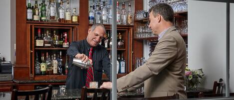 A bar area with a wooden cabinet stocked with liquor bottles and glasses.