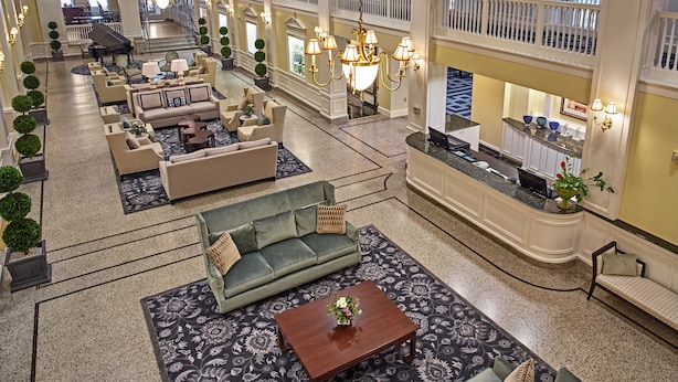 A spacious lobby with multiple seating areas, a grand piano, and a reception desk. - Hotel 24 South (Staunton)