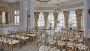 A spacious hall with rows of gold chairs and a large chandelier. - Hotel 24 South (Staunton)