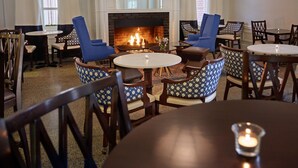 A cozy room with a fireplace, blue and patterned chairs, and a round table with a candle. - Hotel 24 South (Staunton)