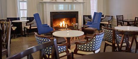 A cozy room with a fireplace, blue and patterned chairs, and a round table with a candle.