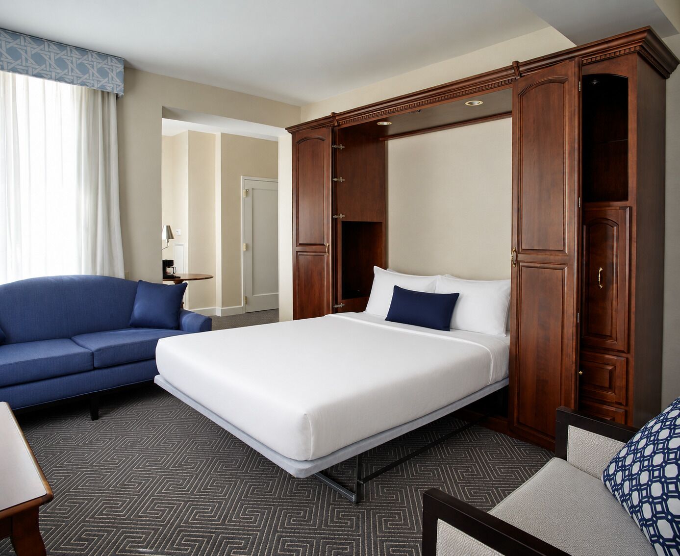 A hotel room with a bed, a sofa, and a wardrobe.