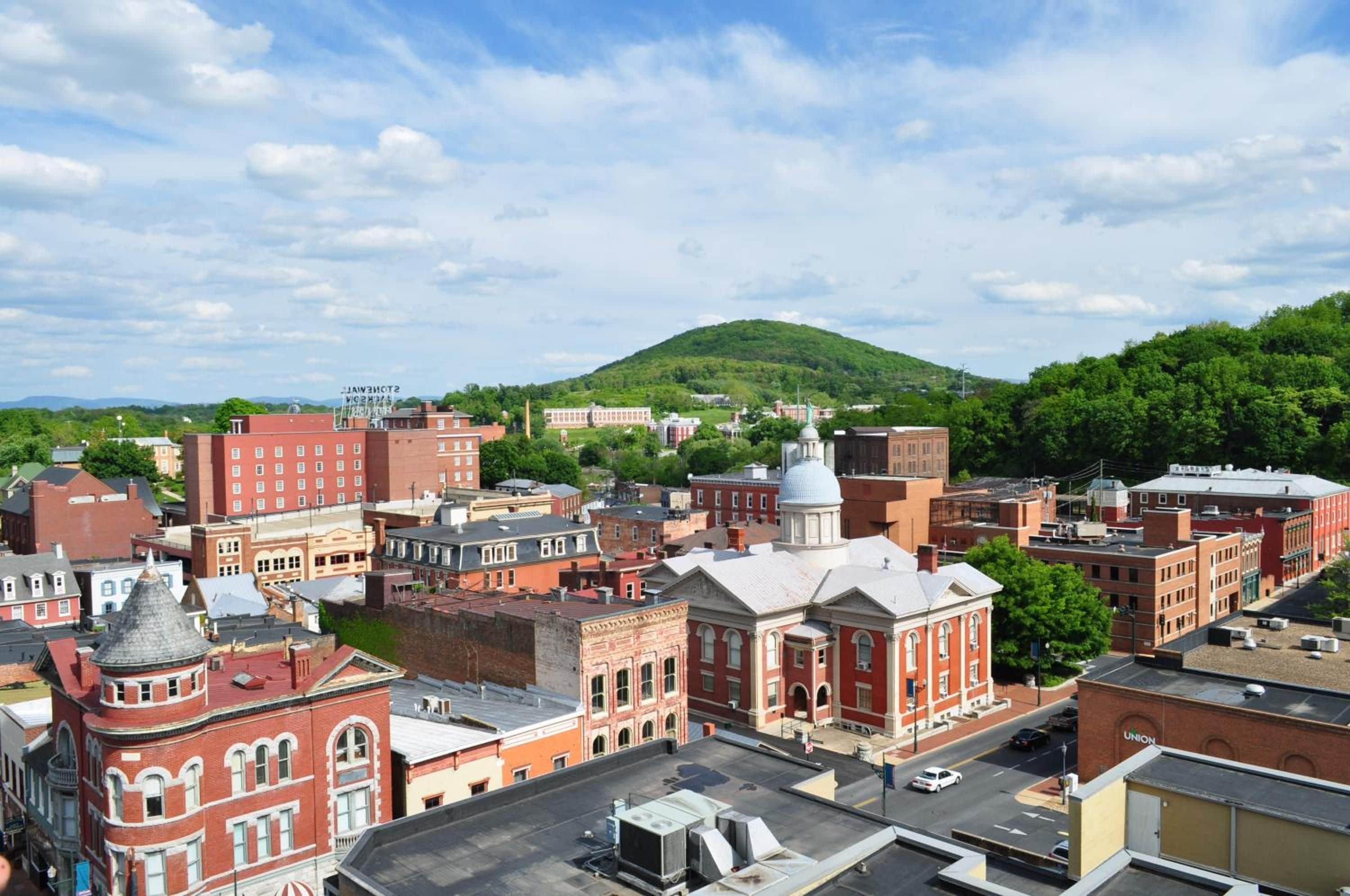 A town with historic buildings, a prominent dome structure, and a hill in the background.