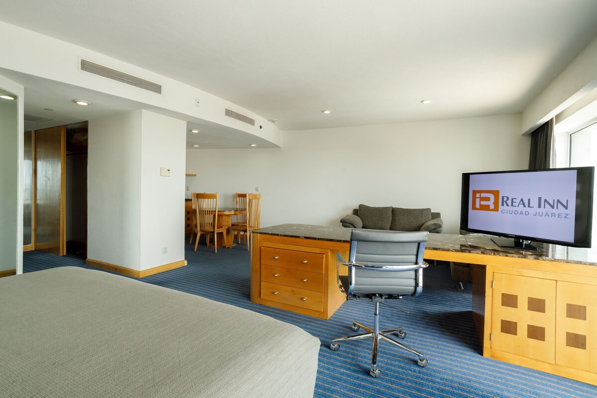 Ein Hotelzimmer mit einem Bett, einem Schreibtisch mit Stuhl, einem Fernseher und einem Holzschrank.