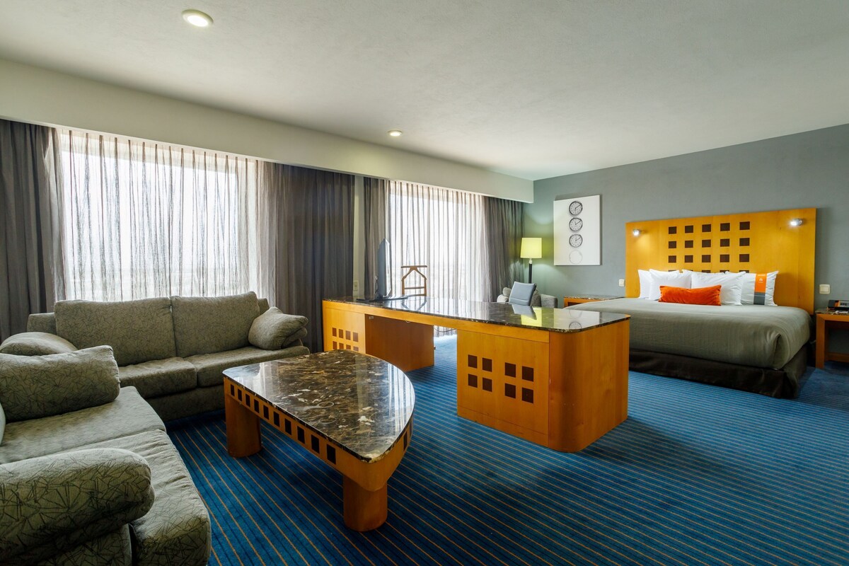 Ein Hotelzimmer mit einer Couch, einem Schreibtisch, einem Bett und einem Couchtisch.