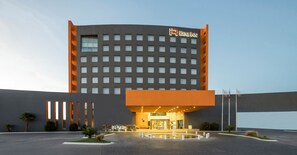 Ein Hotel der Real Inn Kategorie mit modernem Design, mit einem markanten Eingangsbereich und einem Parkplatz.
