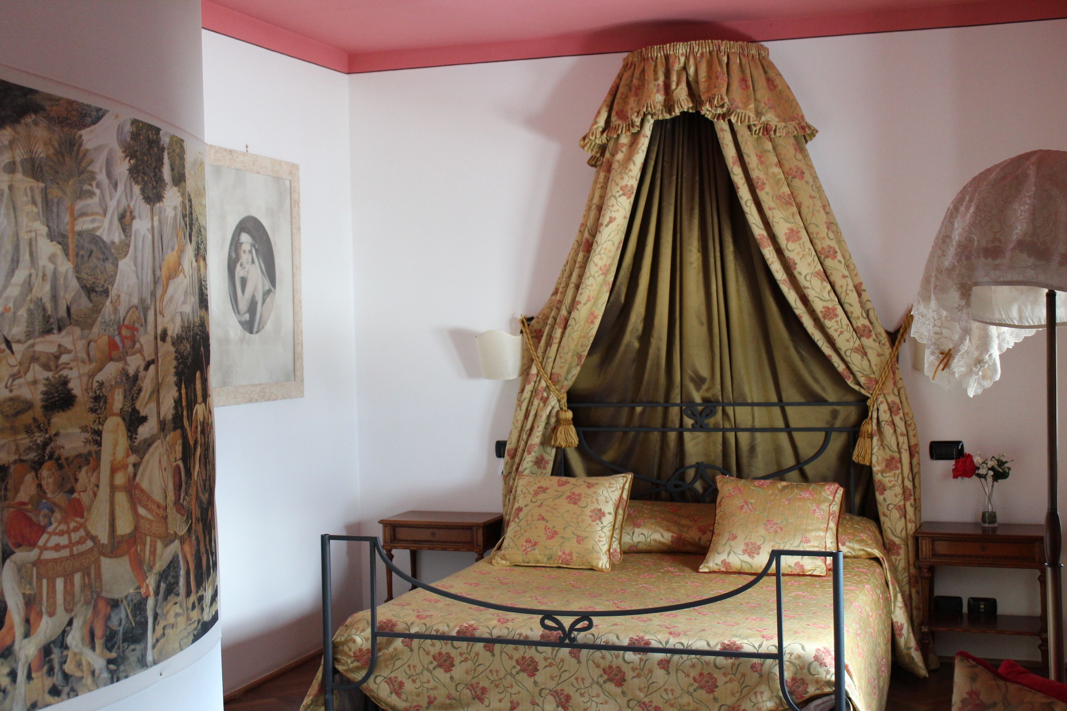 Un dormitorio con cama con dosel, dos mesitas de noche y una lámpara de pared.