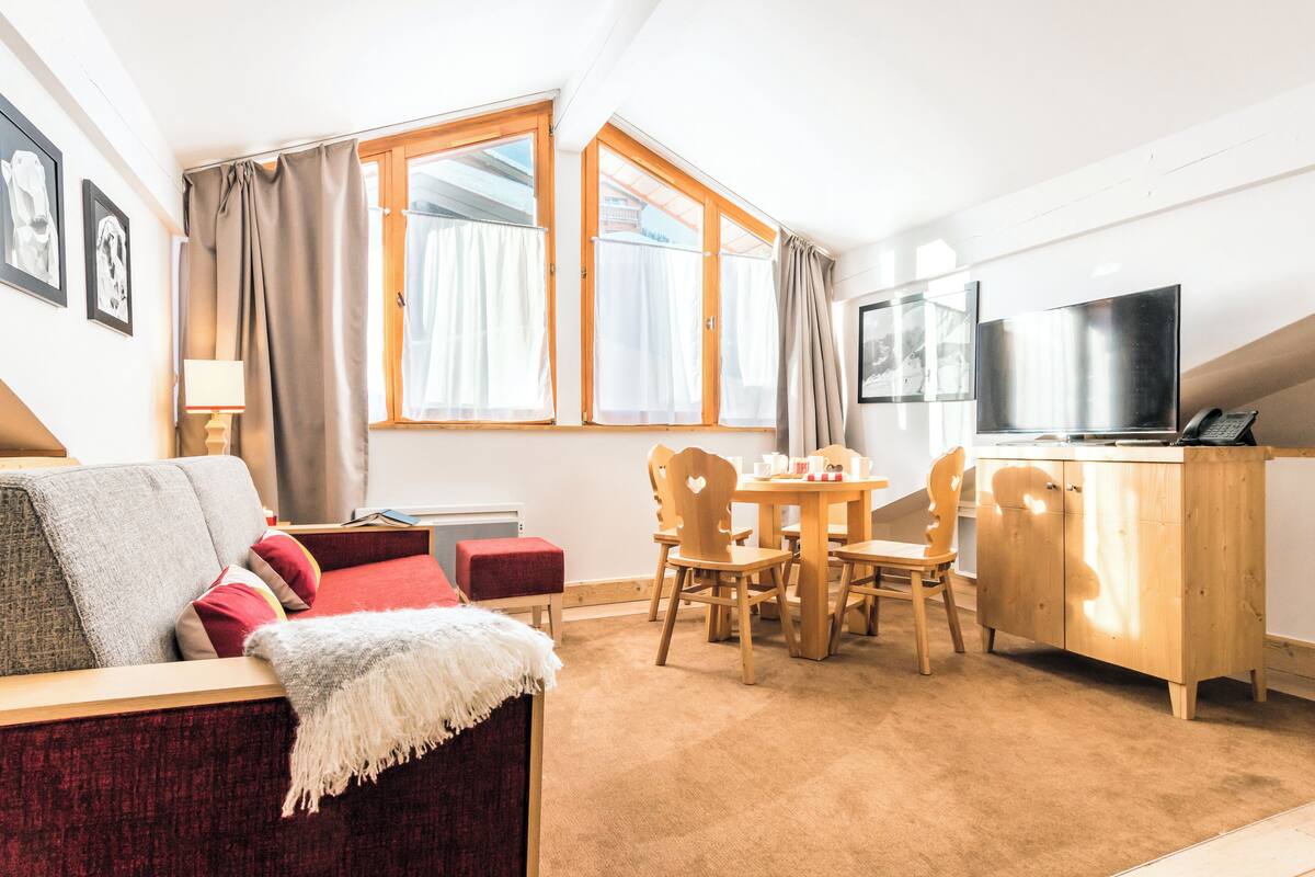 Een gezellige woonkamer met een bank, een klein tafeltje en een televisie.