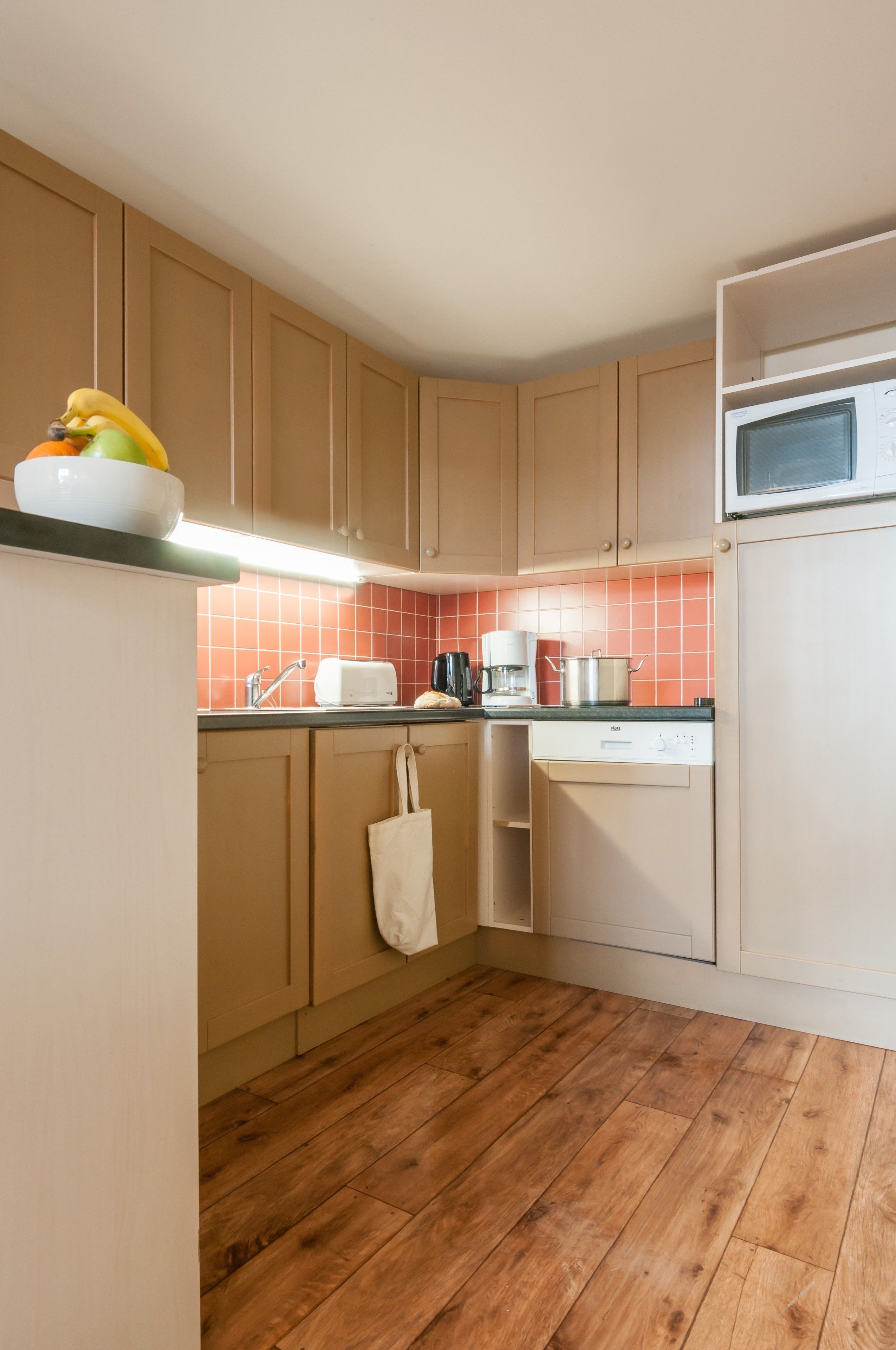 Una cocina compacta con armarios de madera, un microondas, un tostador y una cafetera.