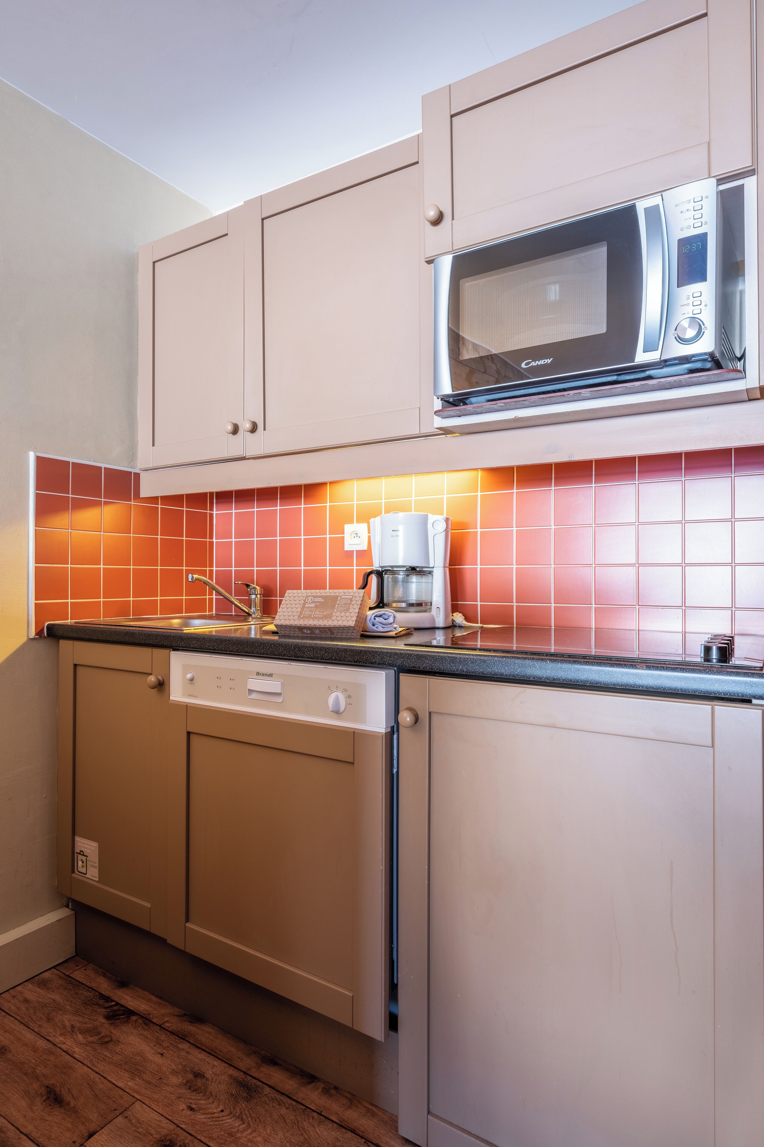 A compact kitchen with a microwave, coffee maker, and dishwasher.