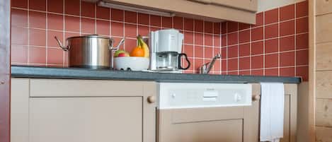 A kitchen with wooden cabinets, a microwave, a coffee maker, and a dishwasher.