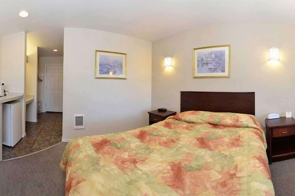 Une chambre d’hôtel équipée d’un lit, d’un bureau, d’une chaise et de deux lampes fixées au mur.