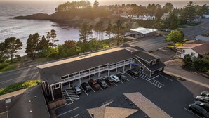 A coastal hotel with a parking lot, a view of the sea, and a small building with a sign. - Travelodge by Wyndham Depoe Bay (Depoe Bay)