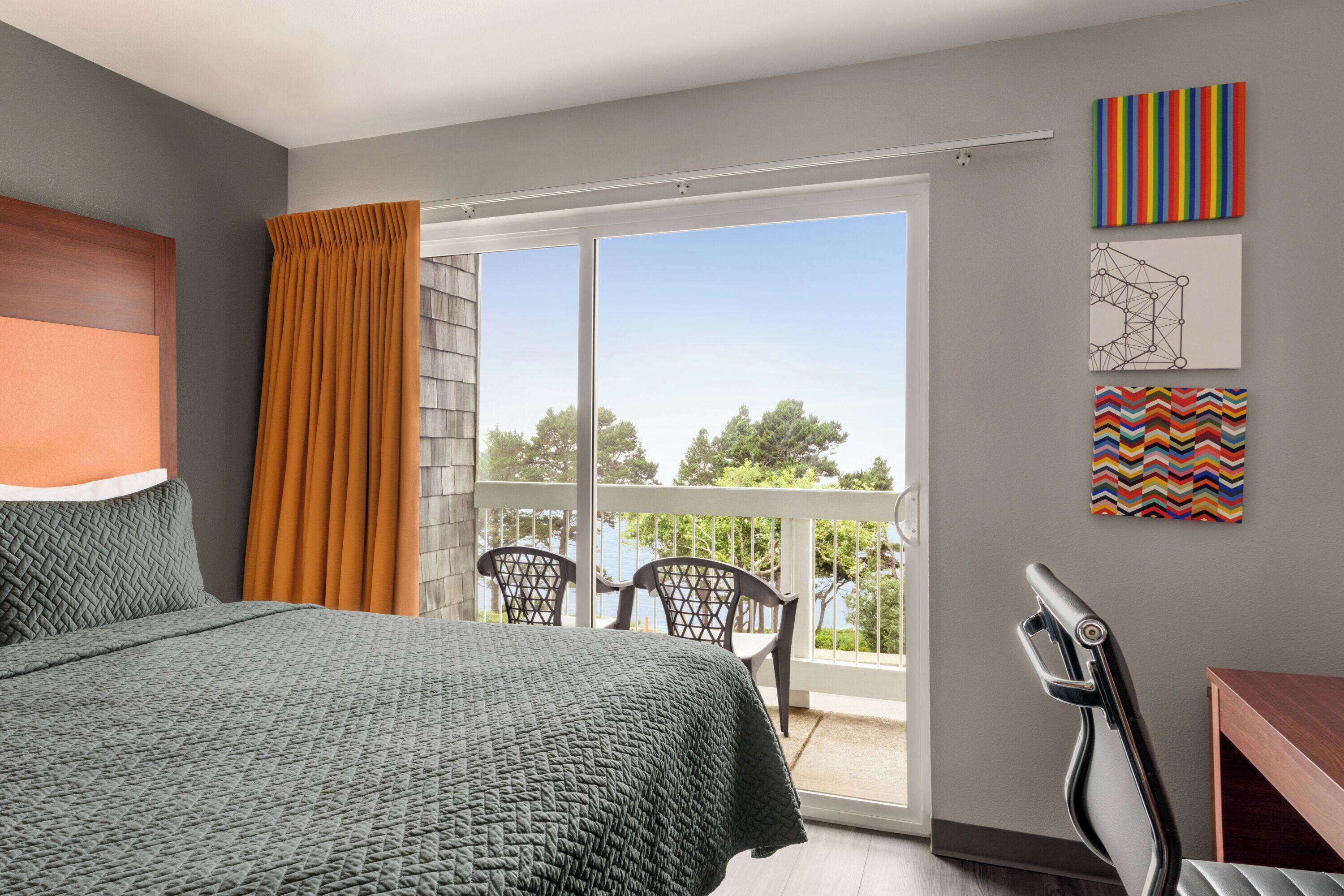 Un dormitorio con cama, vistas al exterior, una silla y una mesa.
