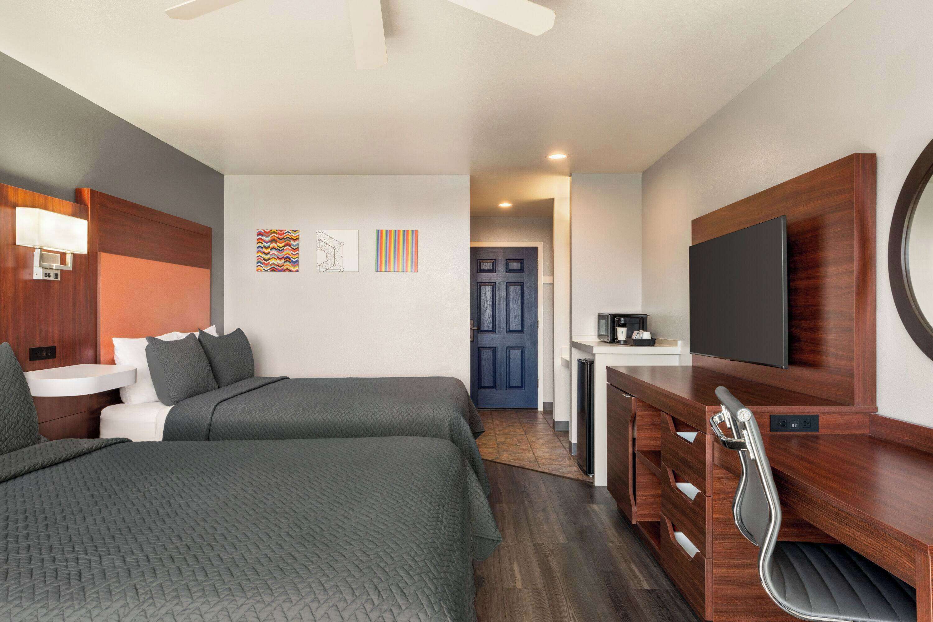 Une chambre d’hôtel avec deux lits, un bureau, une télévision et une salle de bain.