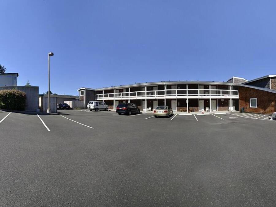 Un bâtiment avec un parking, plusieurs voitures et un ciel bleu dégagé.