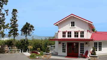 Un edificio bianco con tetto rosso, una porta rossa e un piccolo portico con sedie rosse.