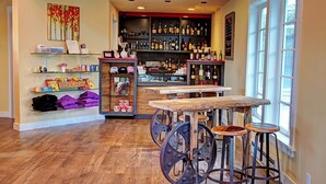 A bar area with wooden stools, a bar counter, and shelves stocked with bottles. - Anacortes Ship Harbor Inn (Anacortes)