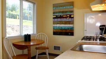 A kitchen with a dining table, chairs, a stove, and a sink.