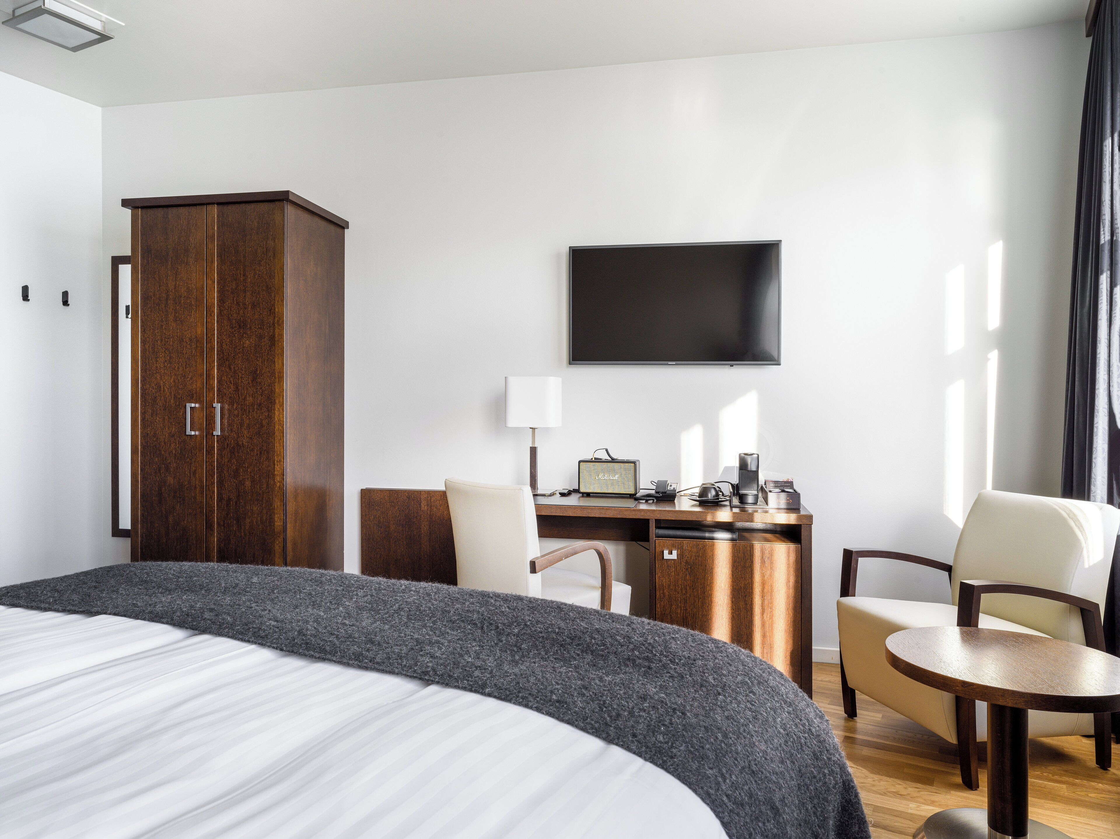 Una habitación de hotel con una cama grande, un escritorio con una silla, un televisor y un armario.