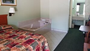A hotel room with a bed, a bathtub, a desk, and a mirror. - Haltom Inn (Haltom City)
