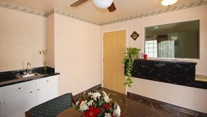 A dining area with a table, chairs, a ceiling fan, a sink, and a window with curtains. - Haltom Inn (Haltom City)