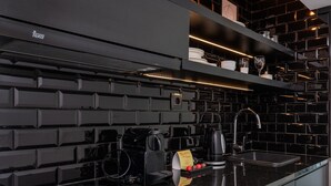 A modern kitchen with a black backsplash, a built-in stove, and a coffee maker.