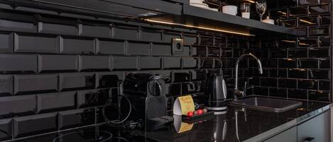 Una cocina moderna con un salpicadero negro, estufa integrada y cafetera.