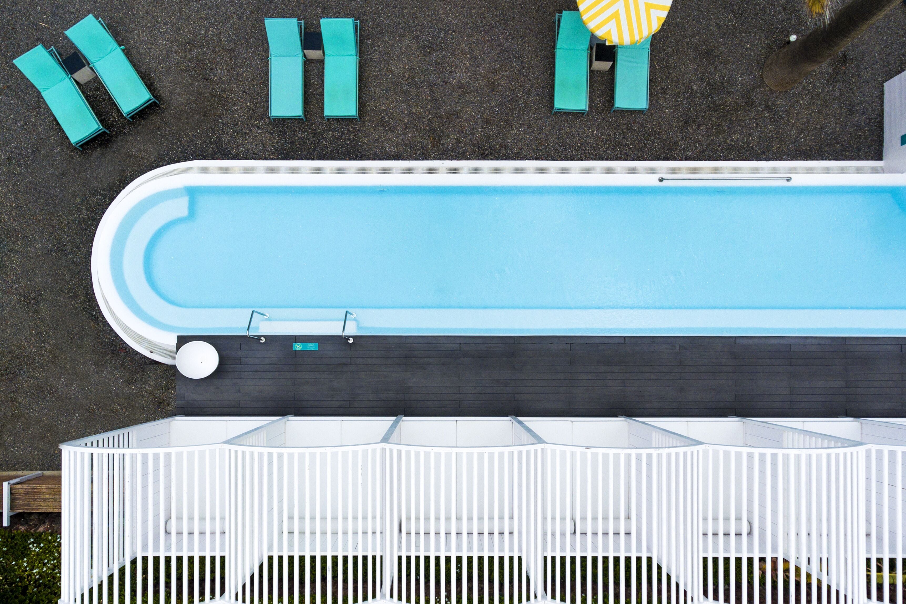 A swimming pool with a white deck and a dark wall.