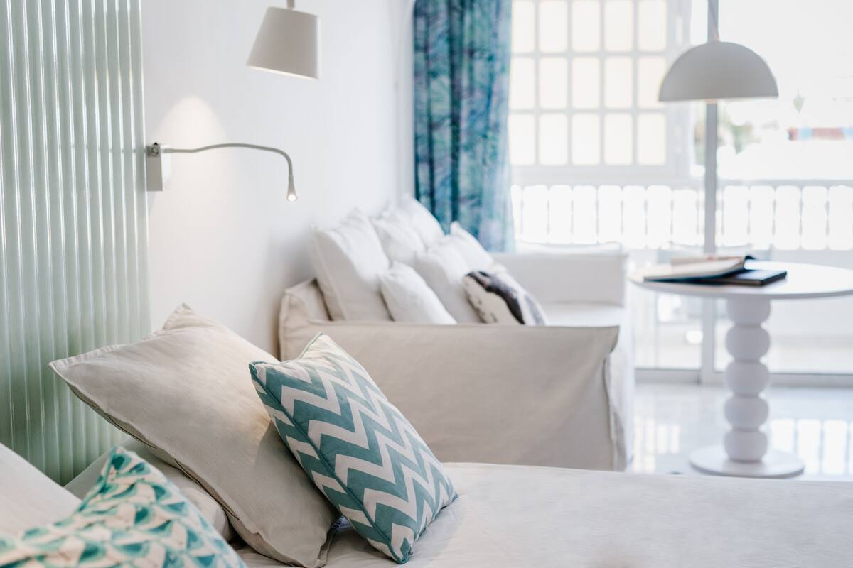 Ein modernes Wohnzimmer mit einer Couch, Zierkissen, einem Beistelltisch und einer Lampe.