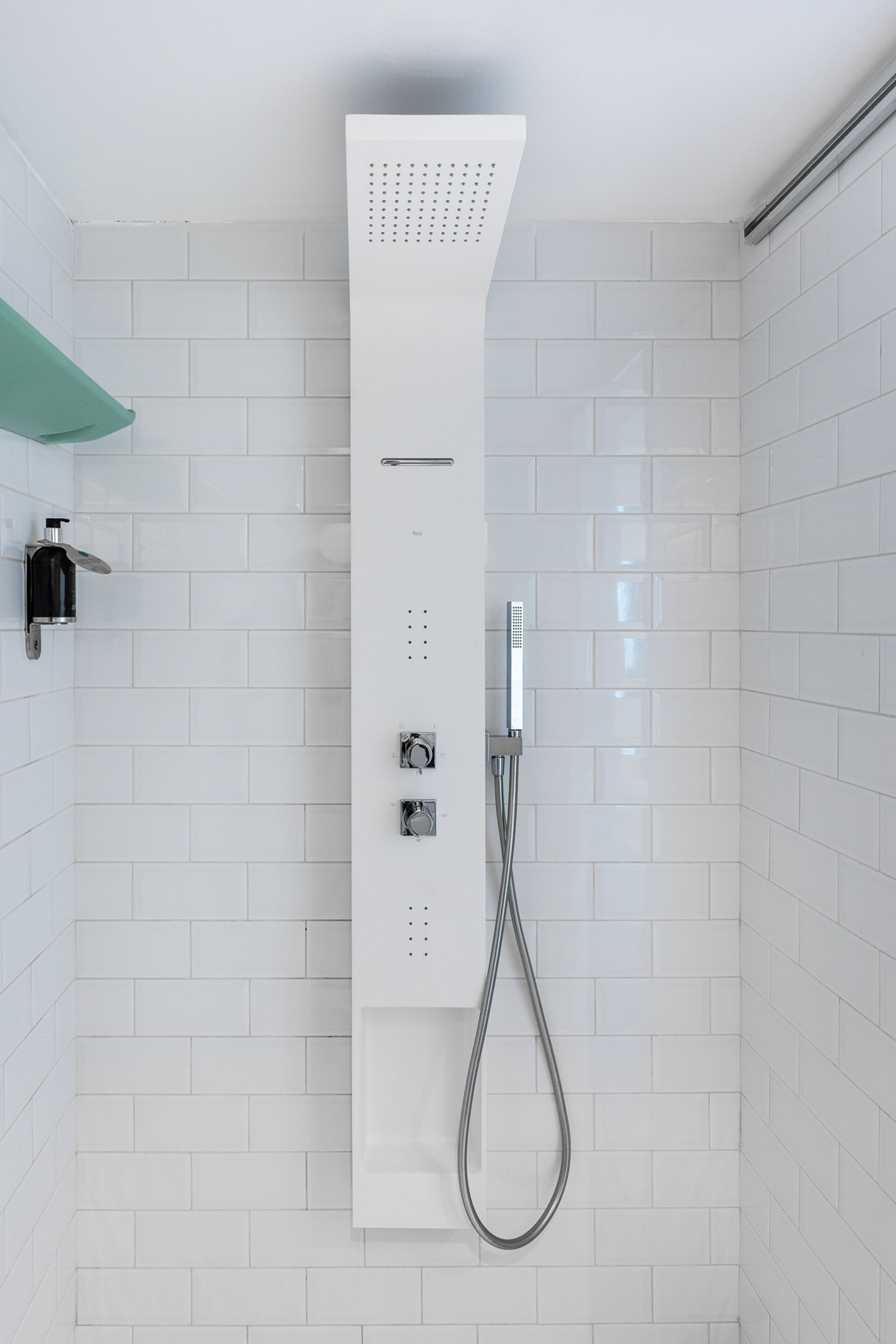 Een moderne douche met bedieningspaneel, douchekop en wandmengkraan.