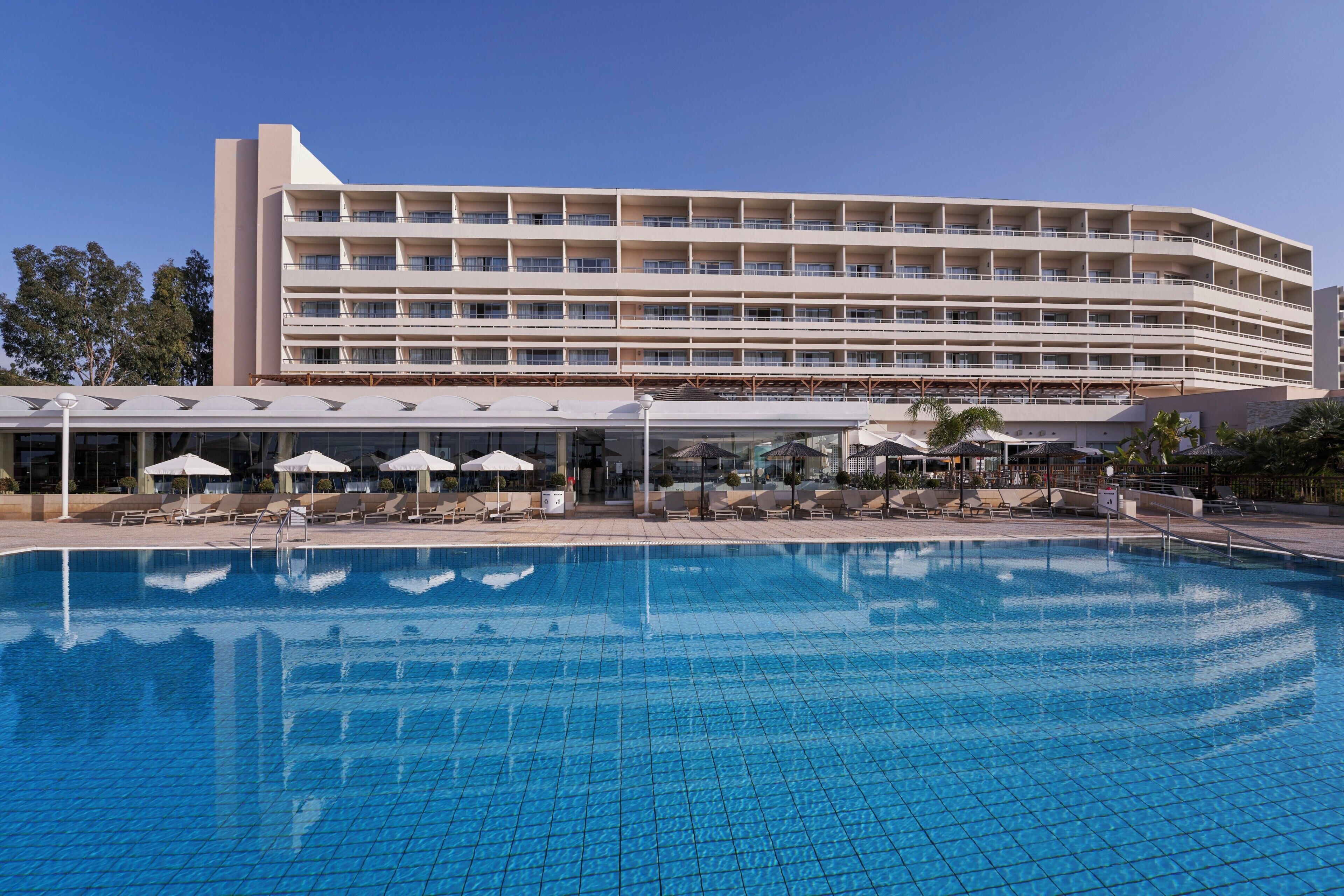 A hotel with a large pool, multiple balconies, and outdoor seating areas.