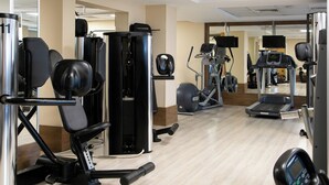 Un gimnasio con diferentes equipos de ejercicio, incluyendo una prensa de piernas, una máquina de prensa de pecho y una caminadora.