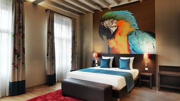A modern bedroom with a large bed, a red rug, wooden flooring, and a mural of a parrot.