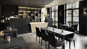 Un área de bar moderna con techo curvo, barra con estantes llenos de botellas y zona de estar con mesas y sillas.