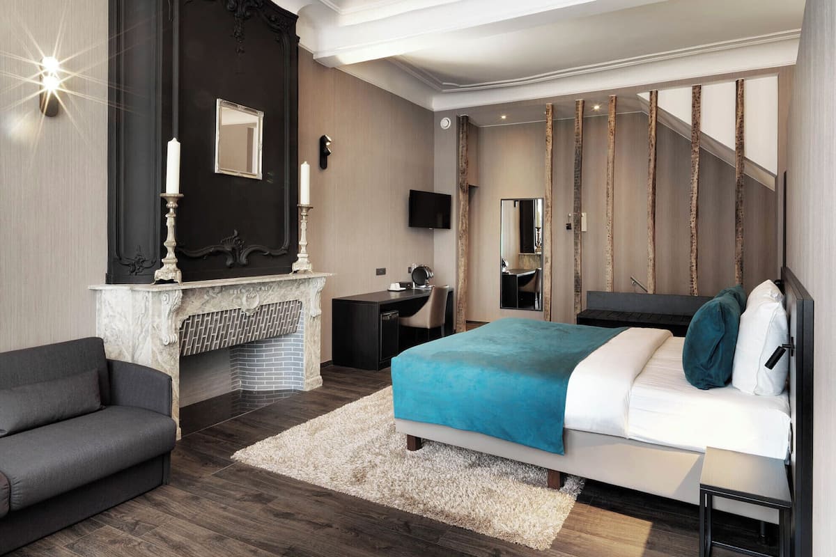 Un dormitorio moderno con una cama grande, una chimenea, un escritorio y una escalera.