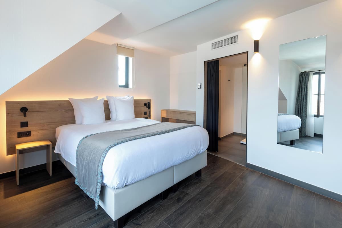 Un dormitorio moderno con una cama grande, mesitas de noche, un espejo y una ventana.