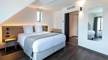 Un dormitorio moderno con una cama grande, mesitas de noche, un espejo y una ventana.