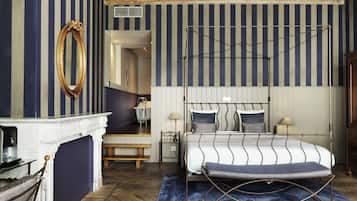 A bedroom with a four-poster bed, a white fireplace, and a striped wall.