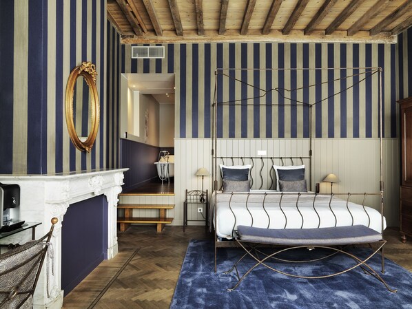 Un dormitorio con cama con dosel, chimenea blanca y pared a rayas.