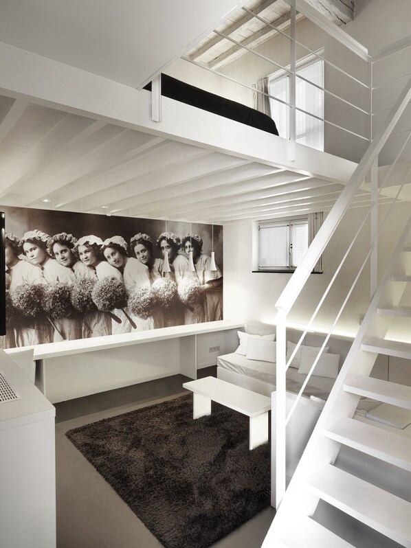 A modern interior with a staircase, a black and white photograph on the wall, and a dark rug.