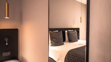 Una habitación de hotel moderna con cama, mesita de noche e iluminación colgante.
