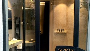 Un baño moderno con mampara de vidrio, ducha y tocador con toallero.