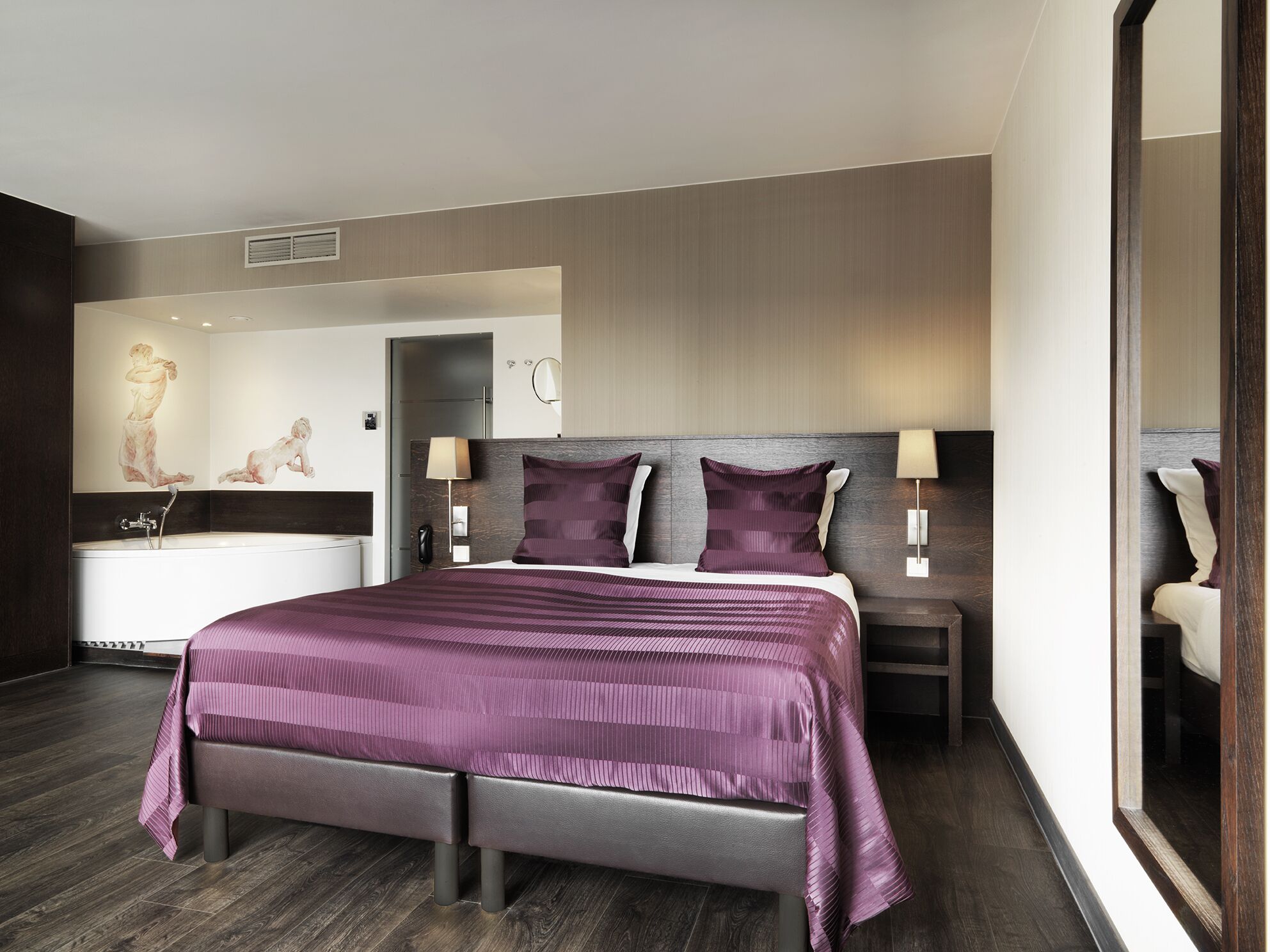 Una habitación de hotel moderna con una cama grande, baño independiente y un espejo.